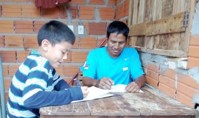 Niño enseña a leer y a escribir a su tío todos los días luego de la escuela