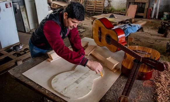 Reo reaviva tradición familiar fabricando guitarras en Tacumbú